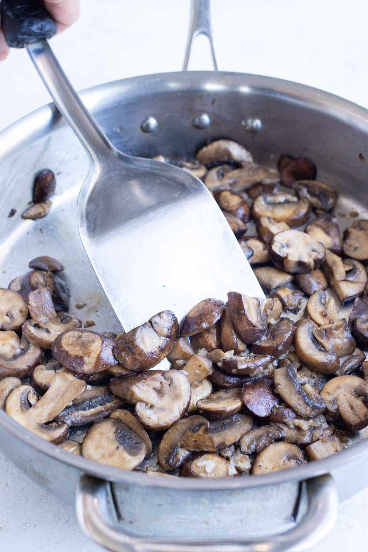 Mushrooms are sauteed in a skillet.