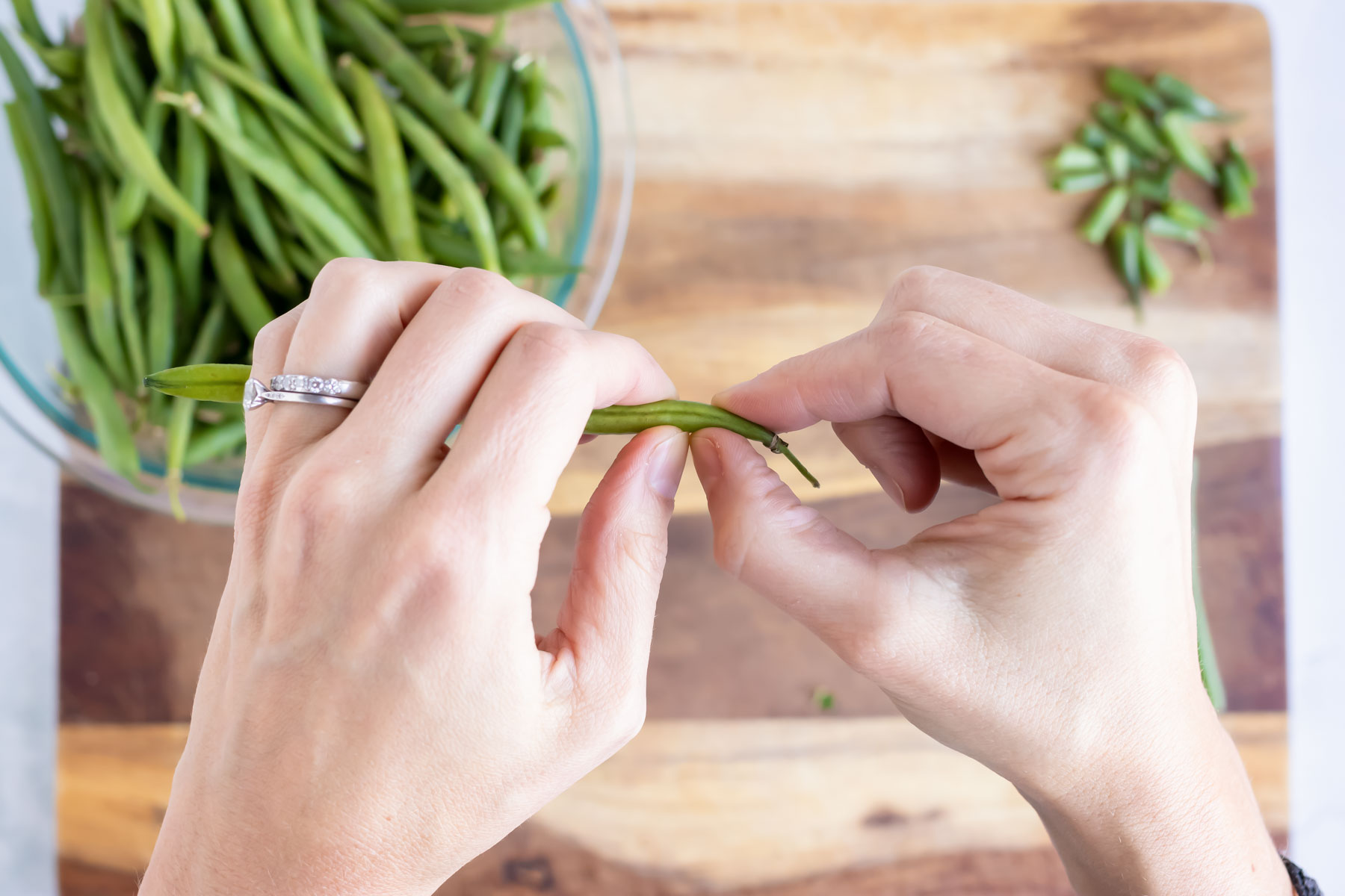 Hands break the ends off of green beans.