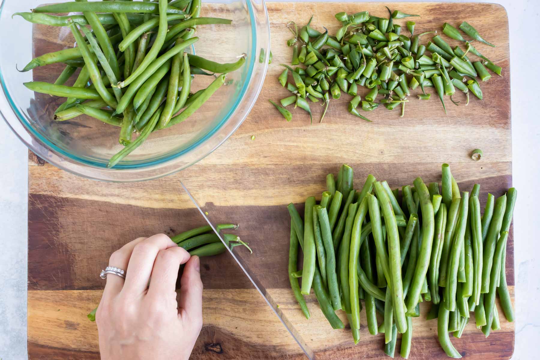 A knife slices the tips off green beans.