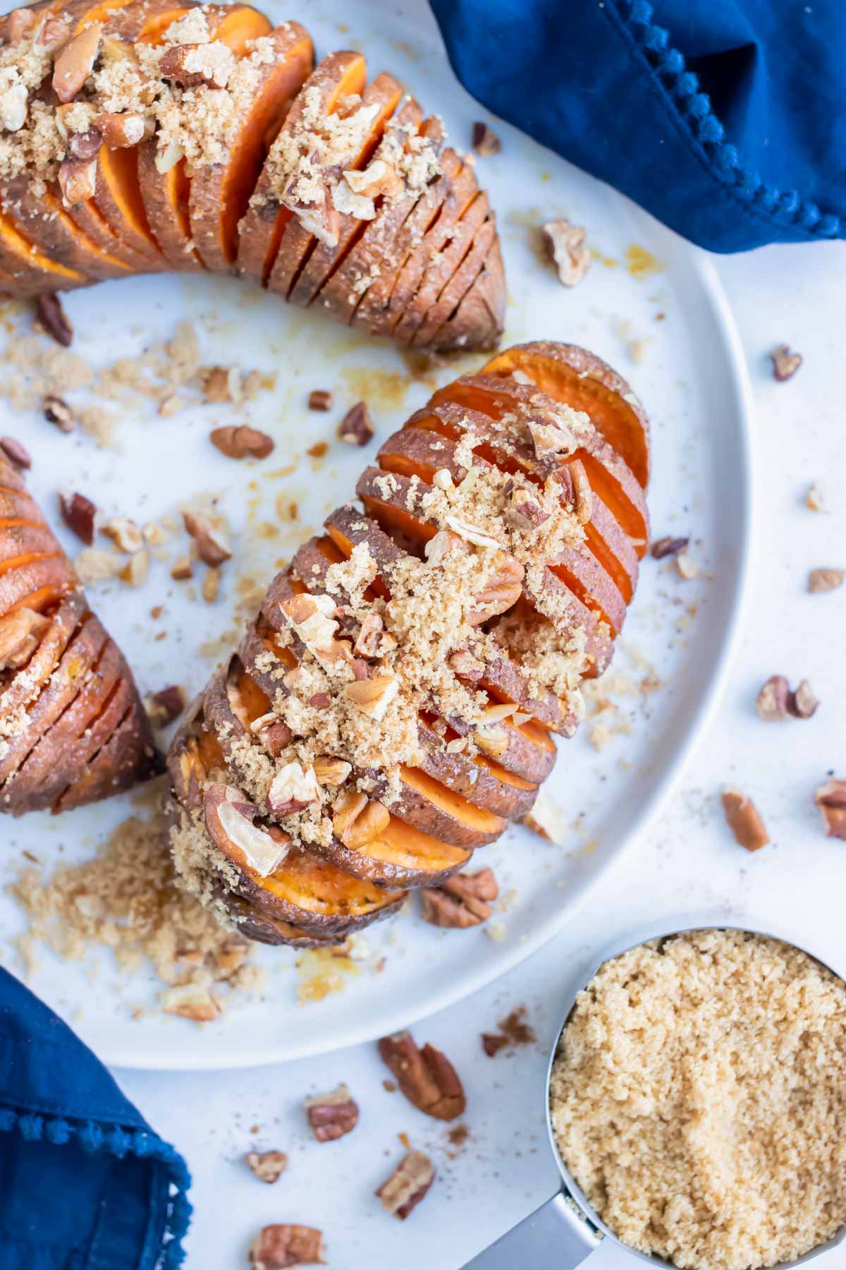 Hasselback sweet potatoes are served with brown sugar, pecans, and cinnamon for a Thanksgiving side dish.