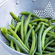 Green beans are drained in a colander after shocking.