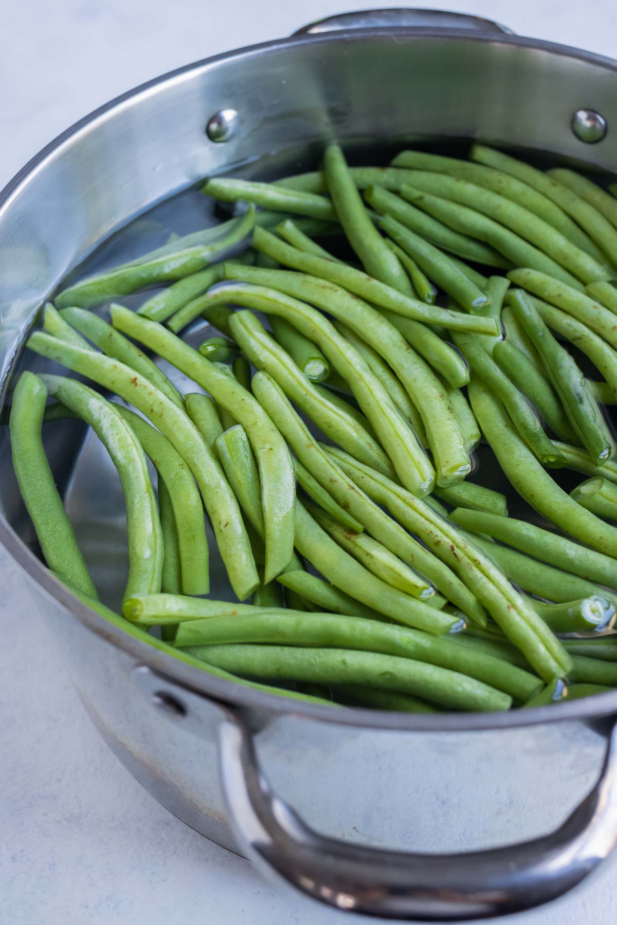 Green beans are placed into a pot of water.