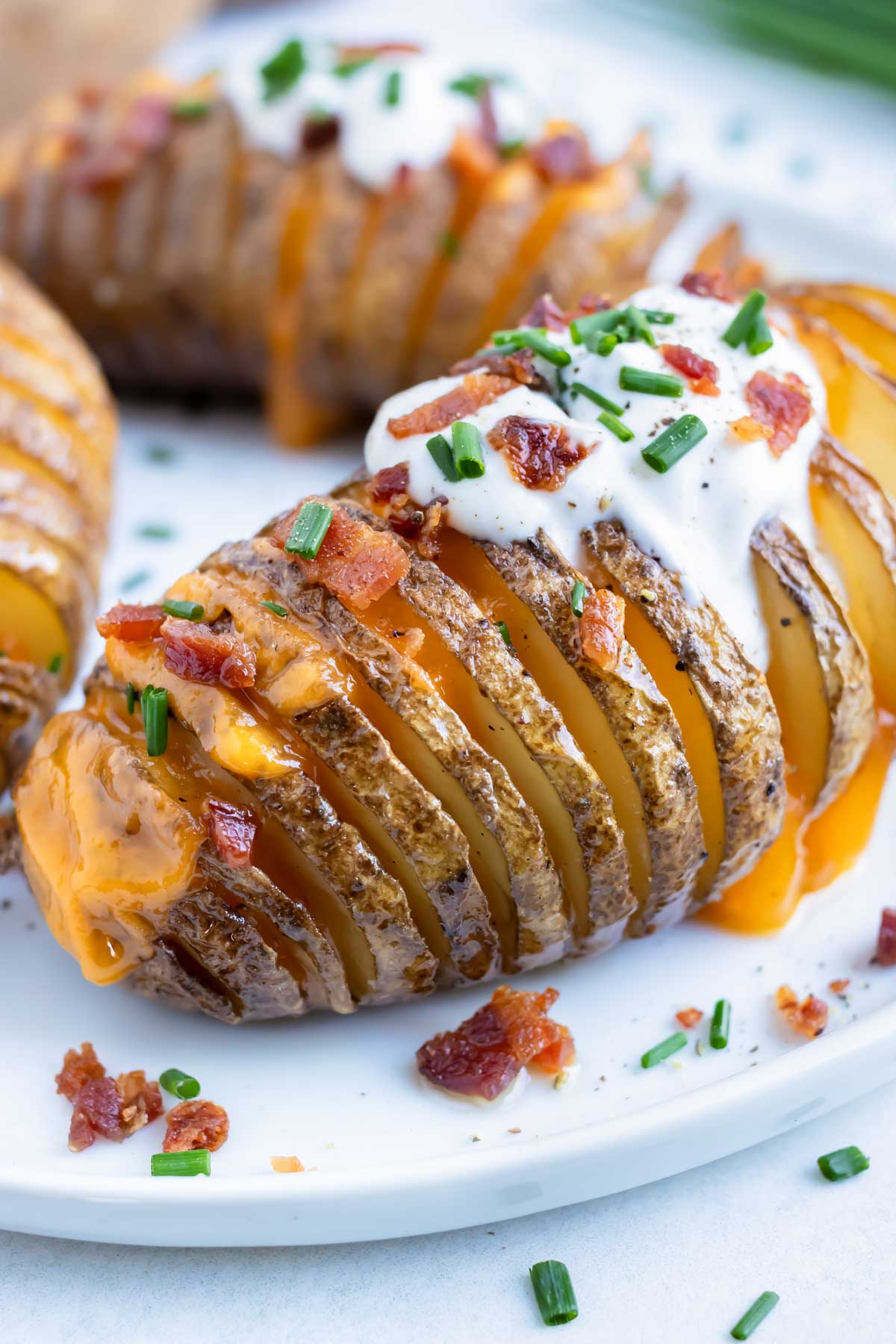 Loaded hasselback potatoes are topped with sour cream and bacon for a Thanksgiving side.