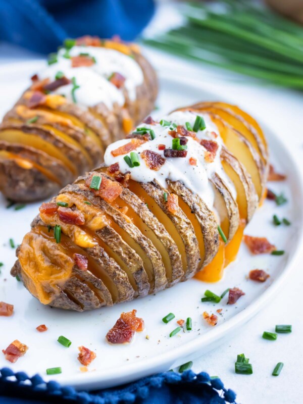 Baked loaded hasselback potatoes are filled with cheese and topped with bacon.