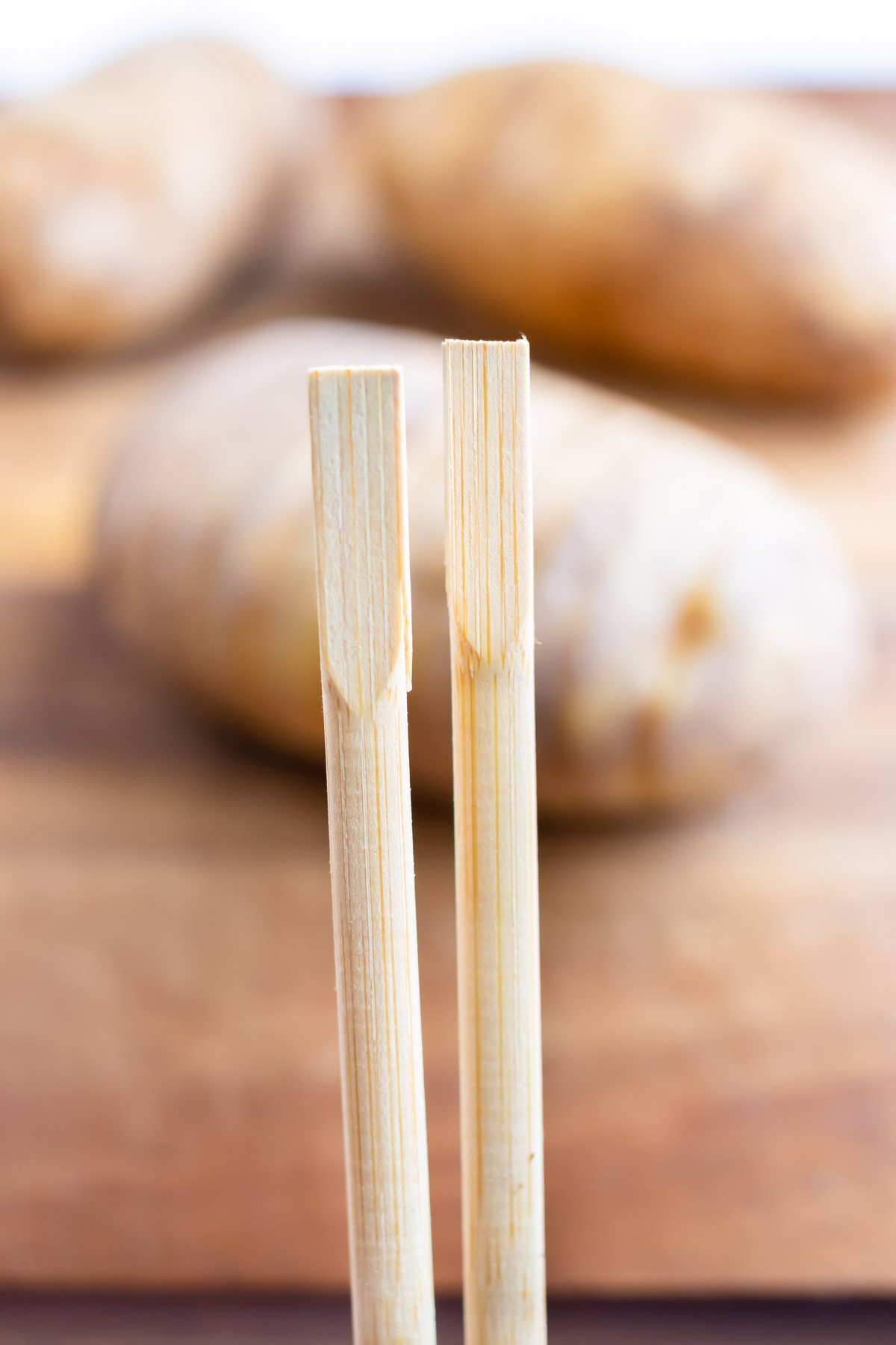 Square chopsticks are used to help cut the potato.