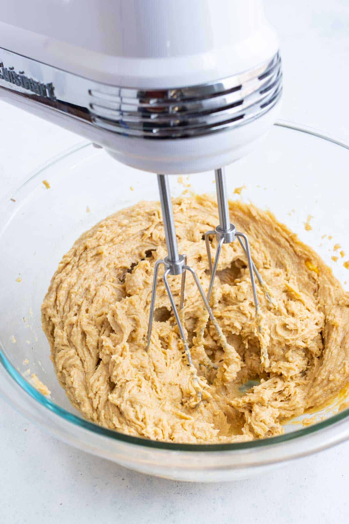 Peanut butter, sugars, and wet ingredients are beaten with a hand mixer.