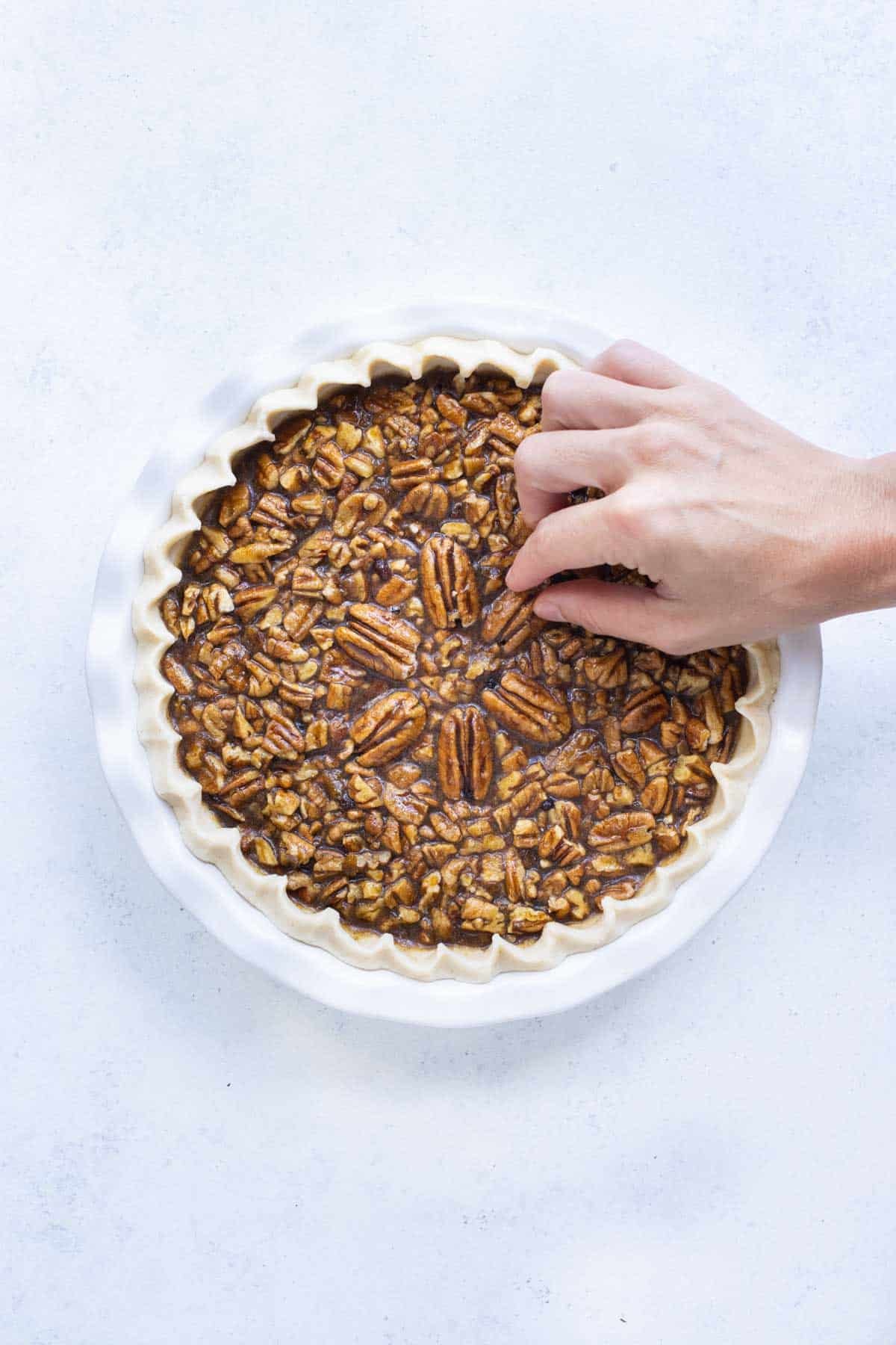 Whole pecan pieces are set out to decorate the center of the pie.