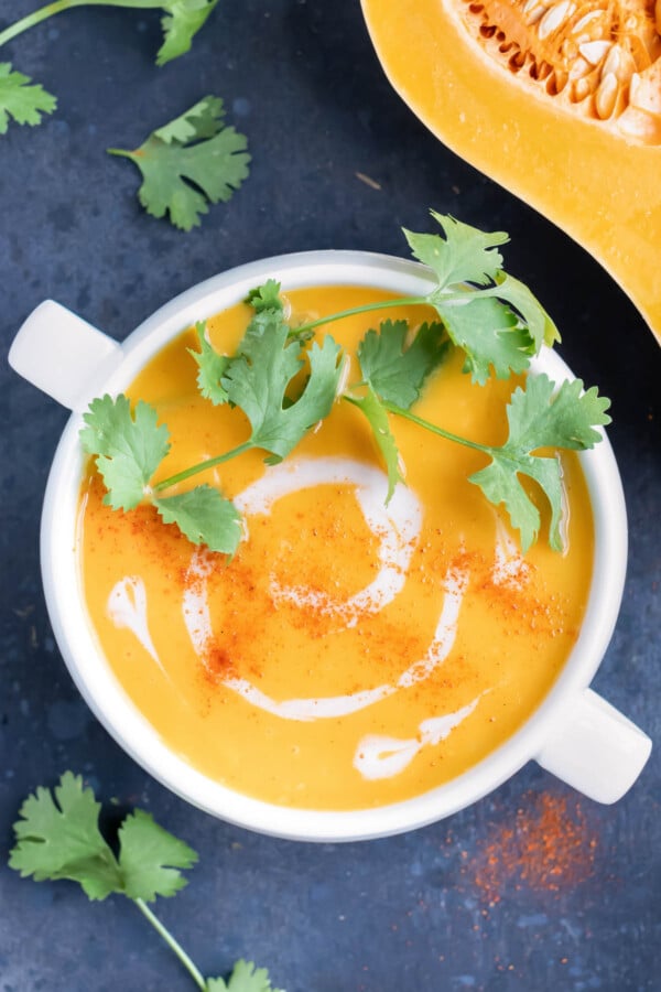 A bowl full of roasted butternut squash soup with a swirl of coconut milk.