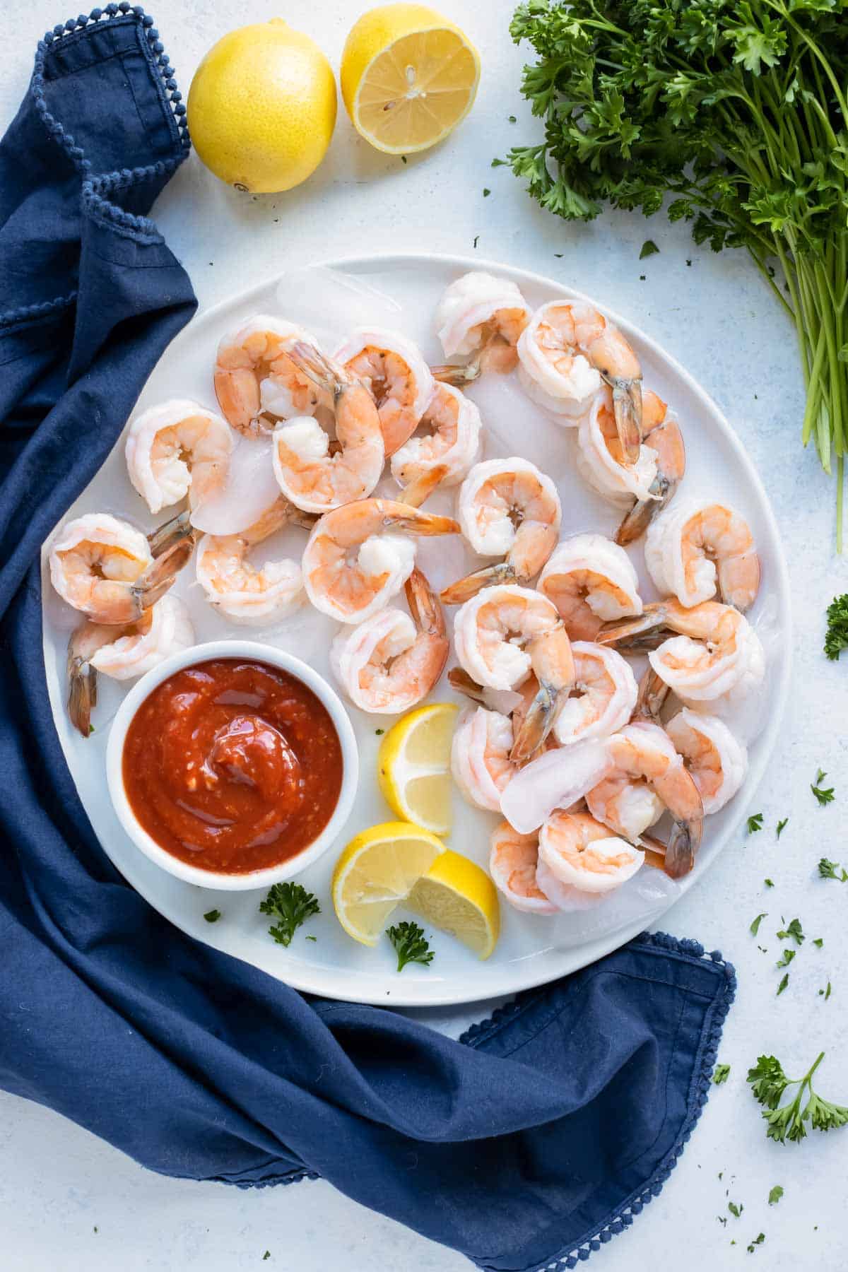 A plate of tender pink shrimp is served with homemade cocktail sauce.