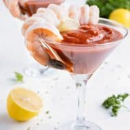 Shrimp is served with a glass of cocktail sauce.
