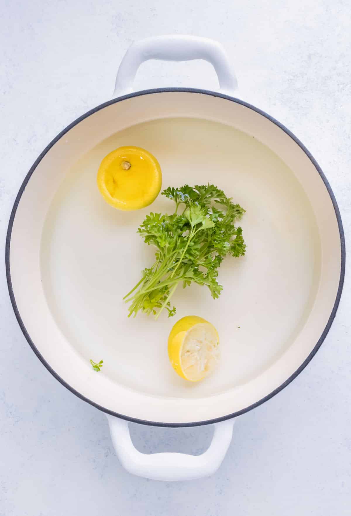 Water, lemons, parsley, salt, and sugar are placed in a pot.