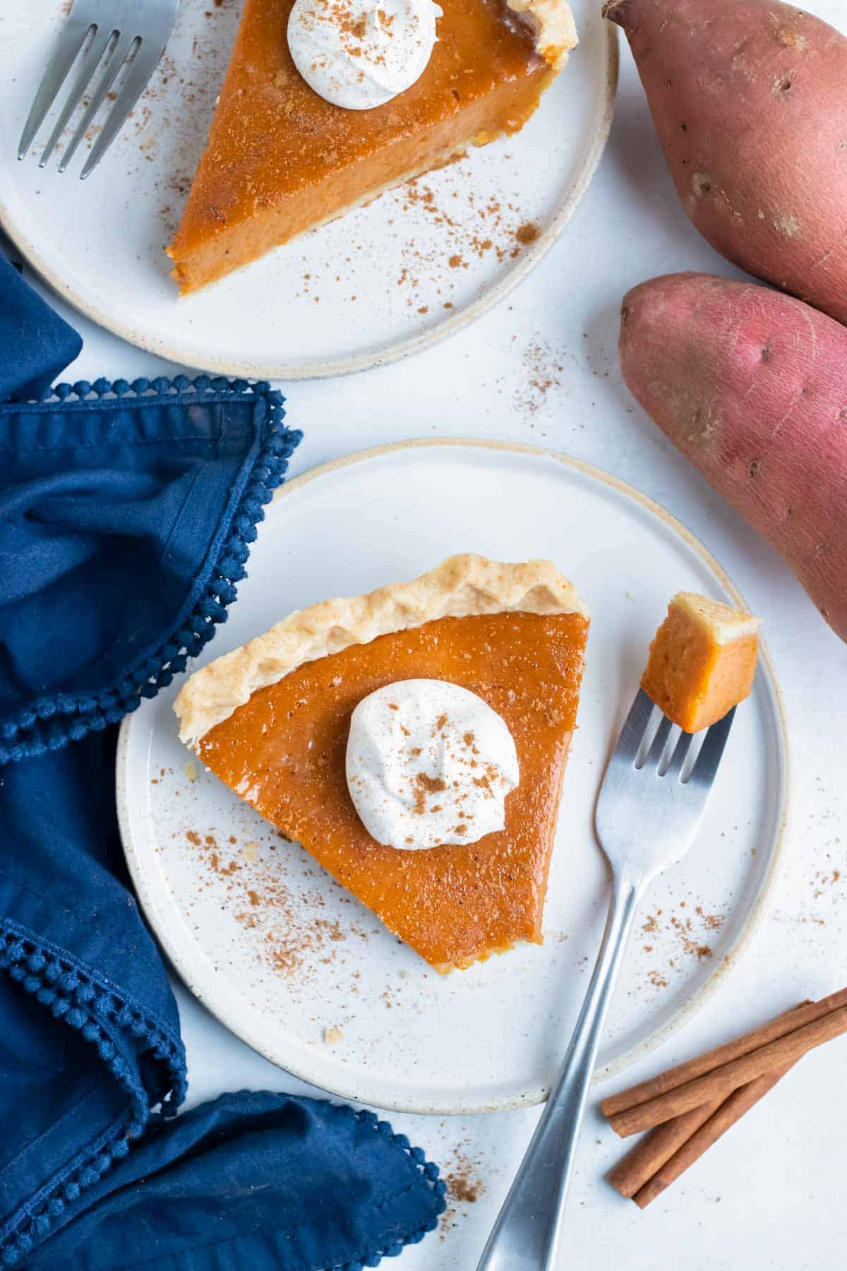 Sweet potato pie is cut into slices and served on white plates for Thanksgiving.