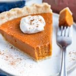 Sweet potato pie served on a plate with a dollop of whipped cream on top.