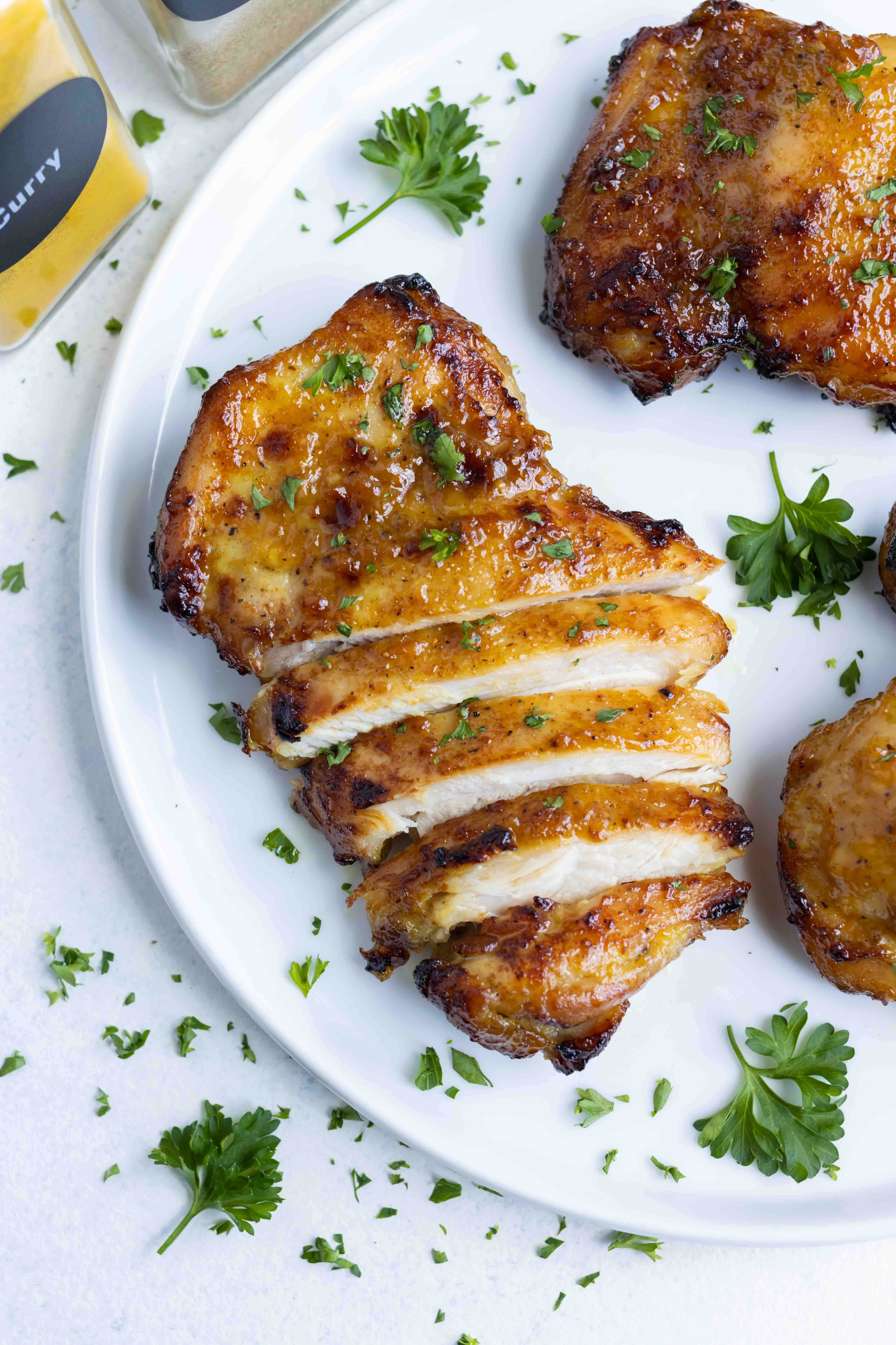 Air Fryer Boneless Chicken Thighs RECIPE sliced and served on a white plate.