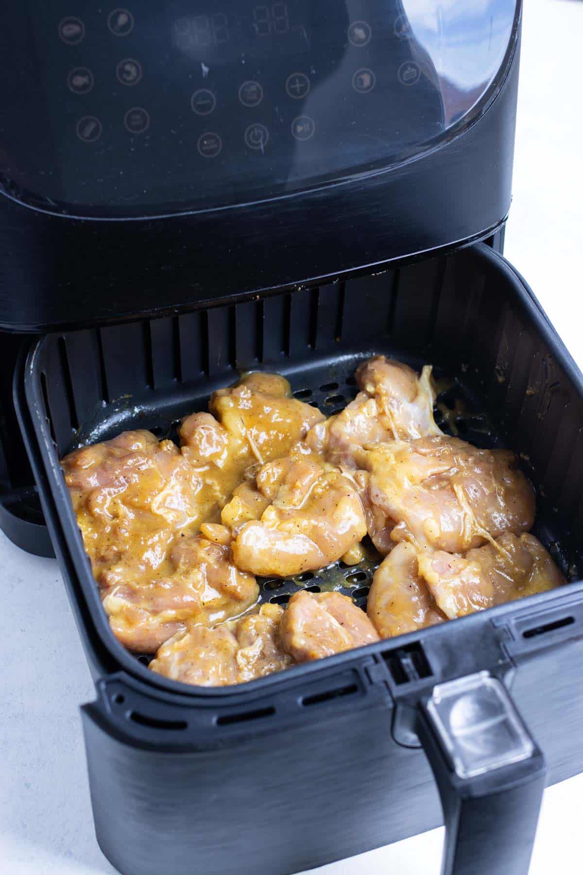 Chicken thighs are placed in the air fryer.