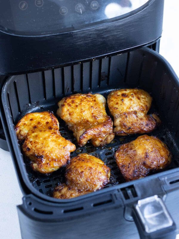 Chicken thighs are spaced out in the air fryer to cook evenly.