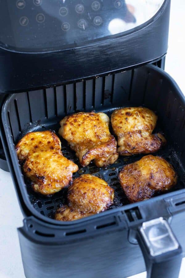 Chicken thighs are spaced out in the air fryer to cook evenly.