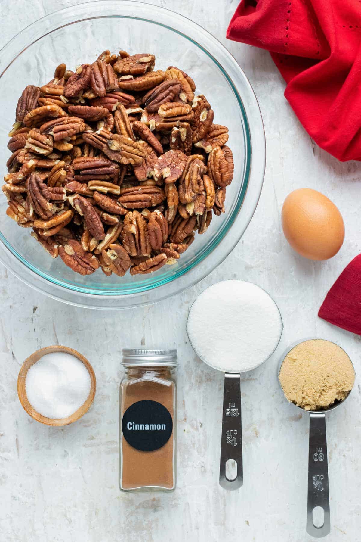 Pecans, cinnamon, sugar, and an egg as the ingredients for an easy, gluten-free candied pecans recipe.