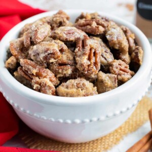Candied pecans with cinnamon sugar in a white snack bowl for a party.