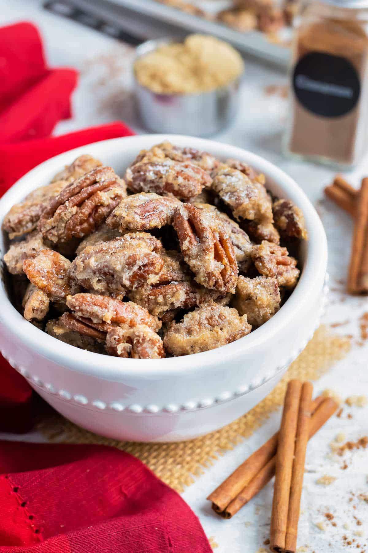 Spiced pecans with cinnamon sugar in a white snack bowl for a party.