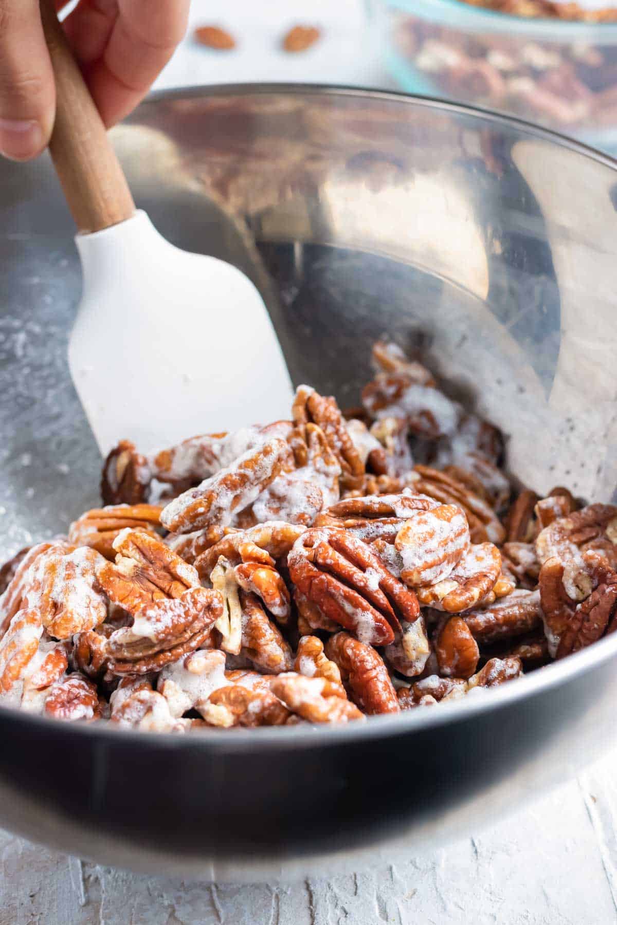 Pecans being tossed in a foamy egg white.