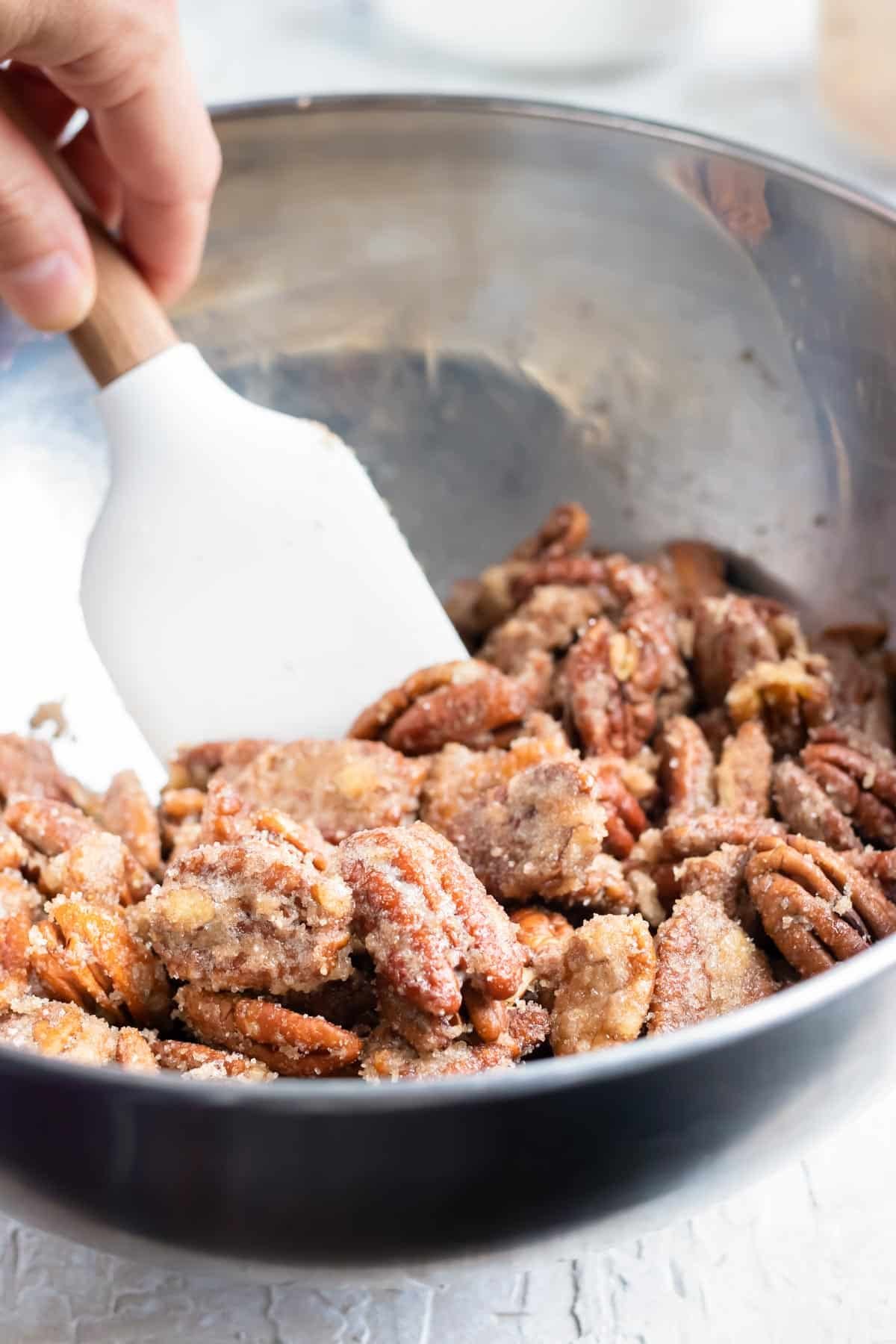 Tossing together cinnamon sugar and pecans for a spiced roasted pecans recipe.