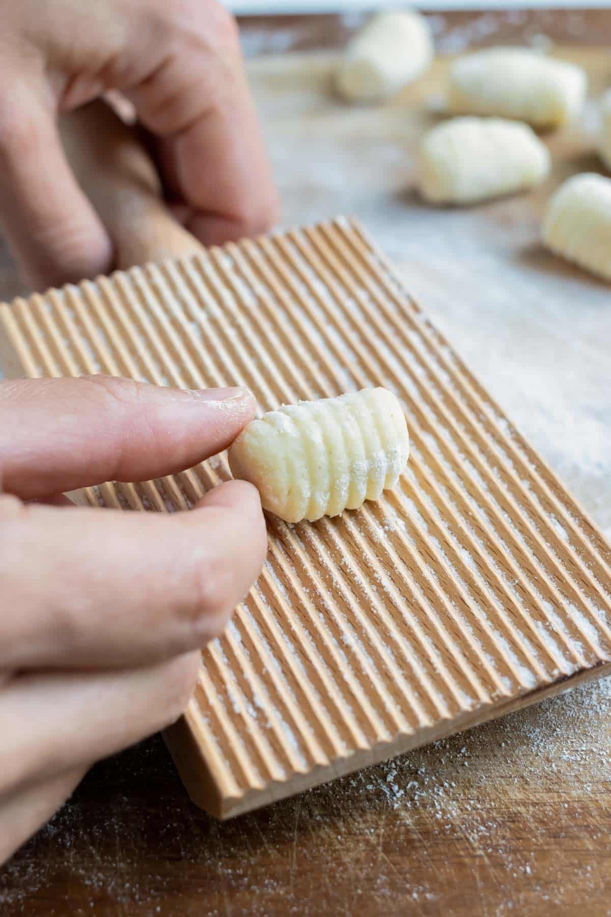 Small dough squares are rolled into the gnocchi shape using a gnocchi board.