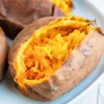 A baked sweet potato that has been cut in half and has salt sprinkled on top.