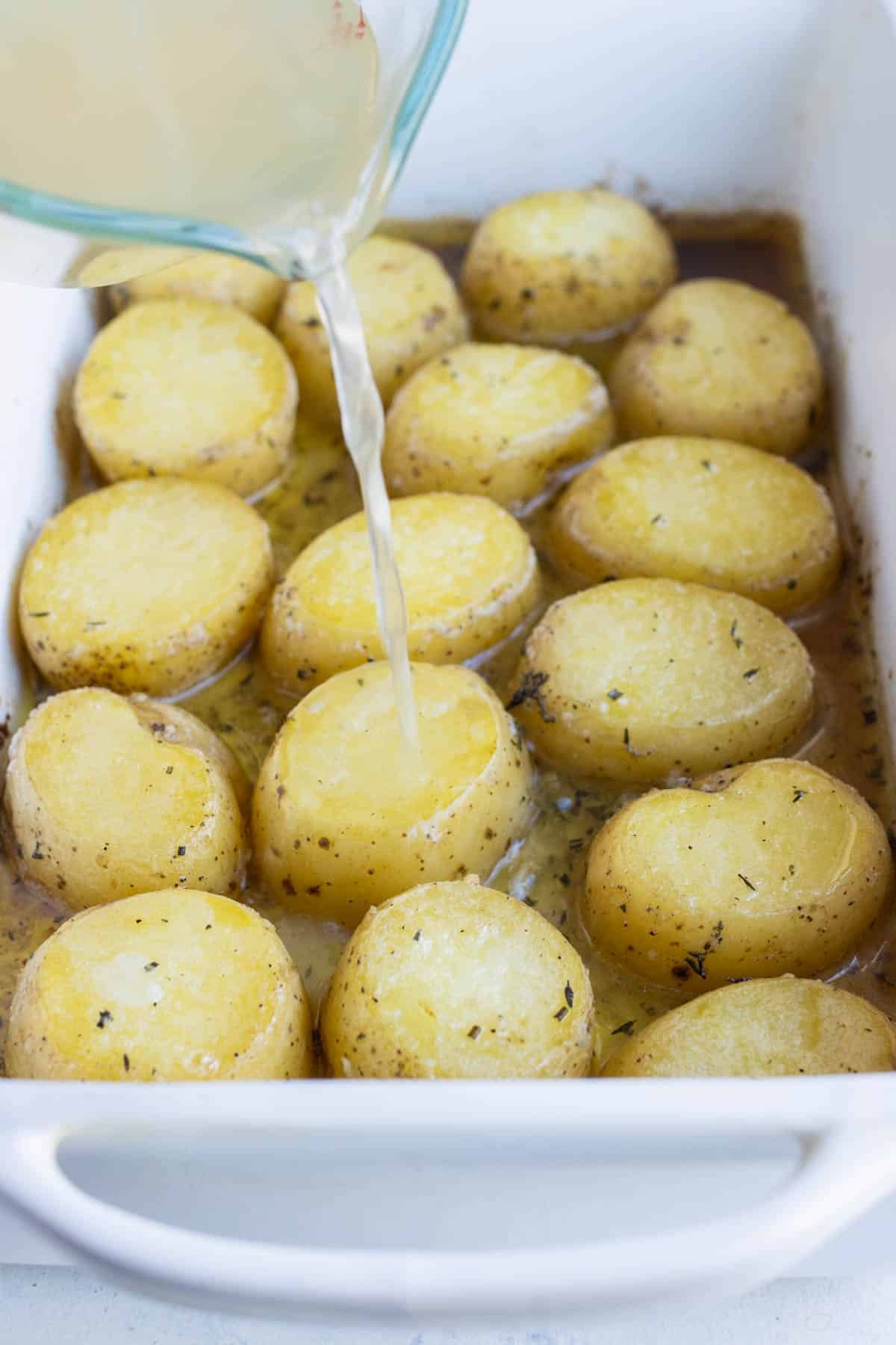 Broth is poured over partially baked potatoes.