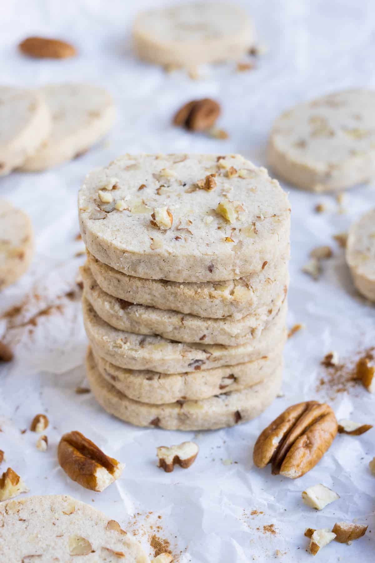 A stack of Pecan Sandies is surrounded by nuts.