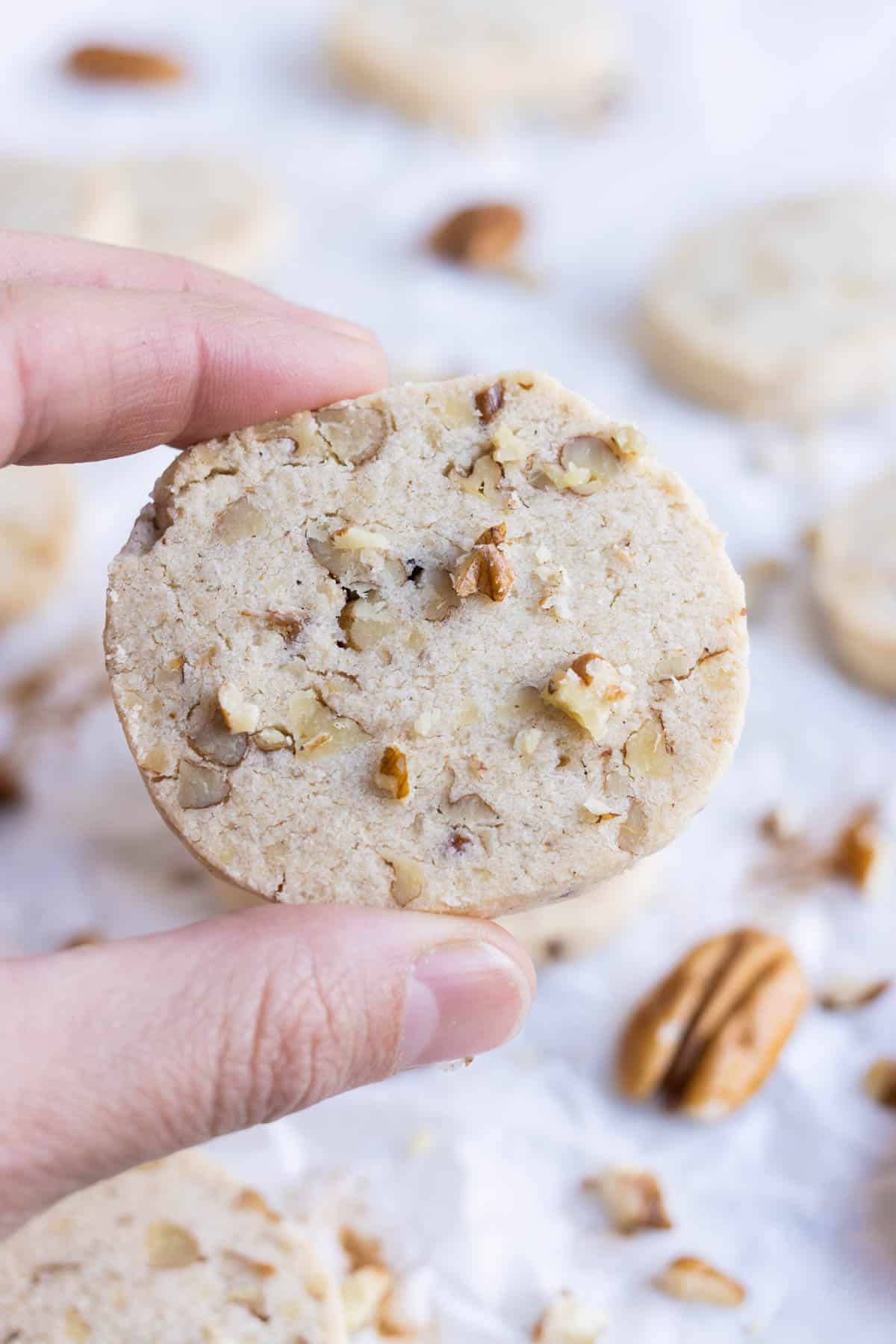 A hand holds a pecan shortbread cookie.