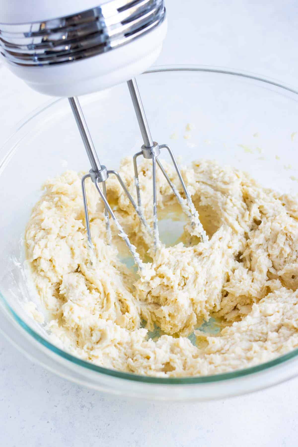 A hand mixer beats the egg, butter, and sugar together.
