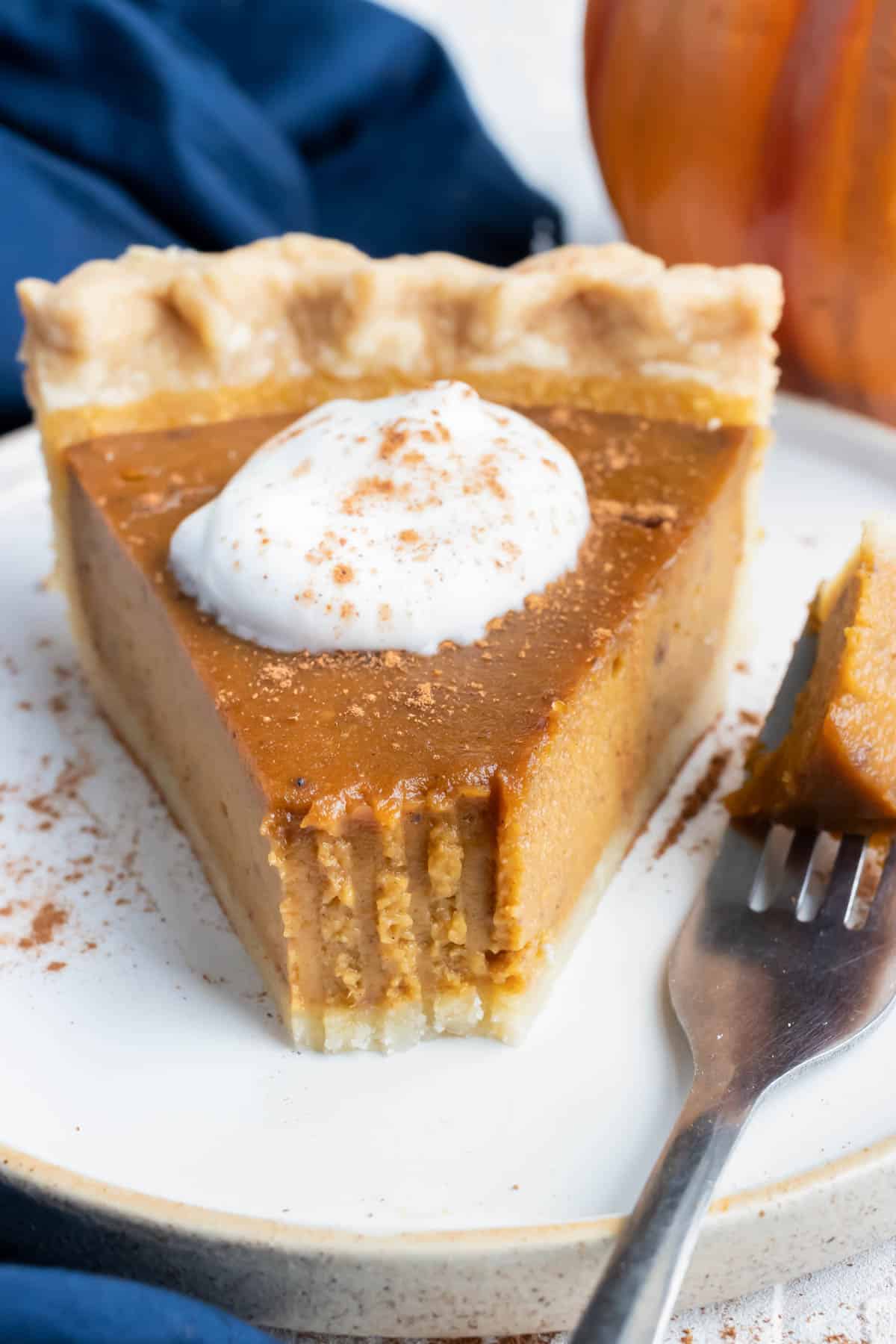 A slice of previously frozen pumpkin pie on a plate with a bite taken out.
