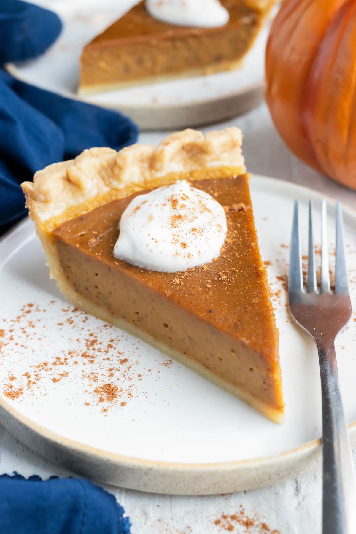 A slice of homemade pumpkin pie with whipped cream on a plate.