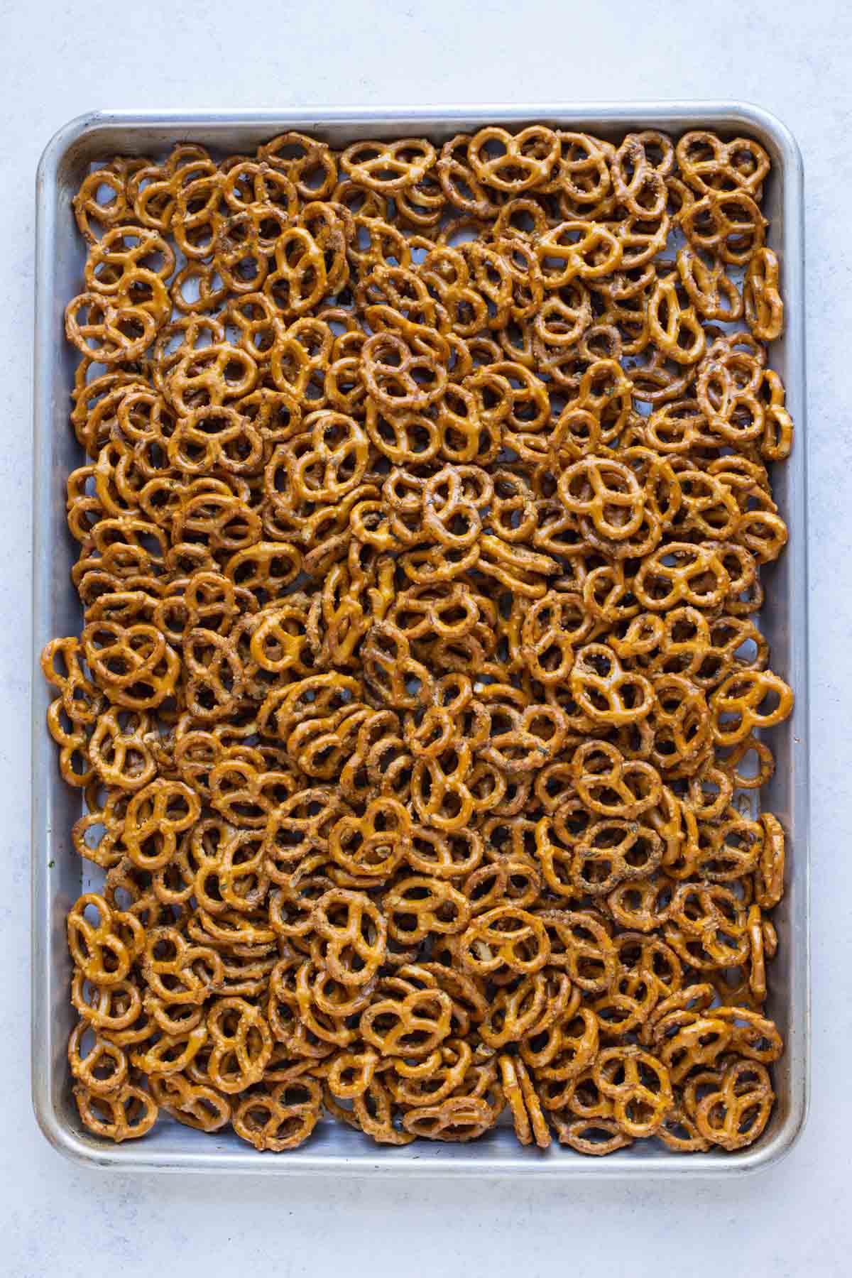 A large baking sheet is full of seasoned pretzels.