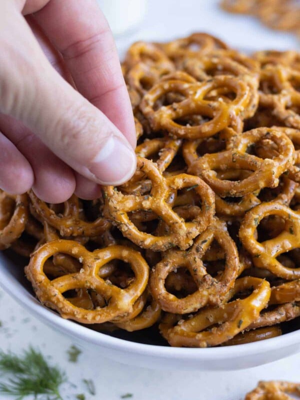 A hand picks up a pretzel seasoned with ranch.