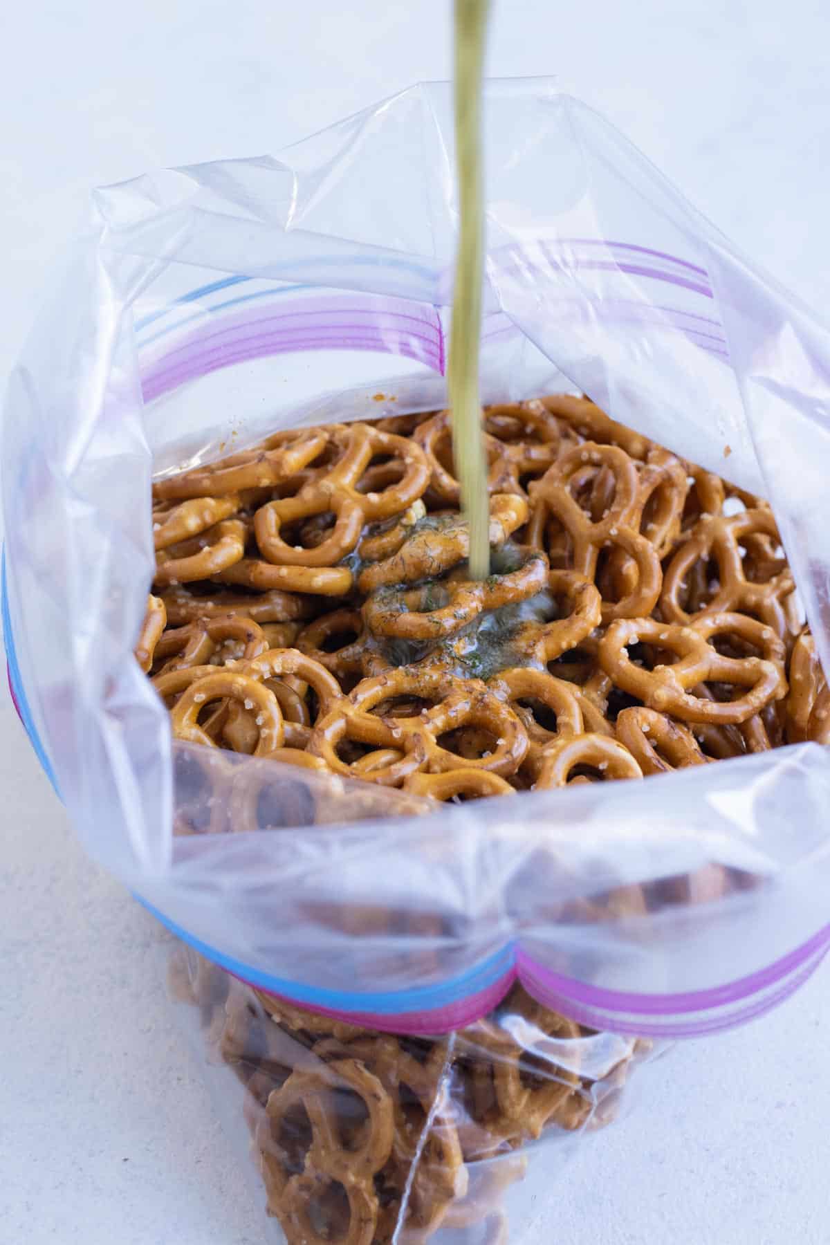 A butter sauce with ranch is poured over pretzels in a bag.