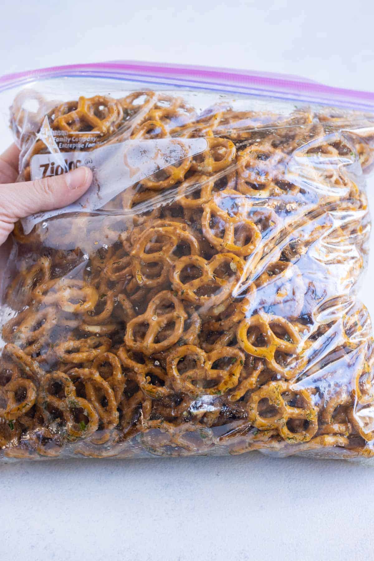 Butter, herbs, and pretzels are tossed together in a bag.