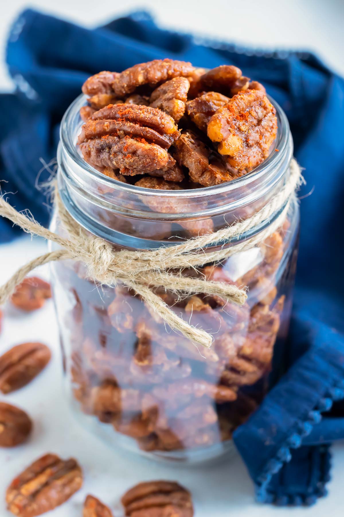 Sweet and spicy pecans are put in a mason jar for a low-carb snack.
