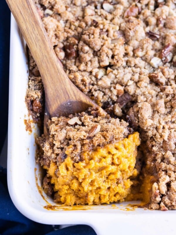 Sweet potato casserole with pecans and brown sugar is served with a spoon for the holidays.