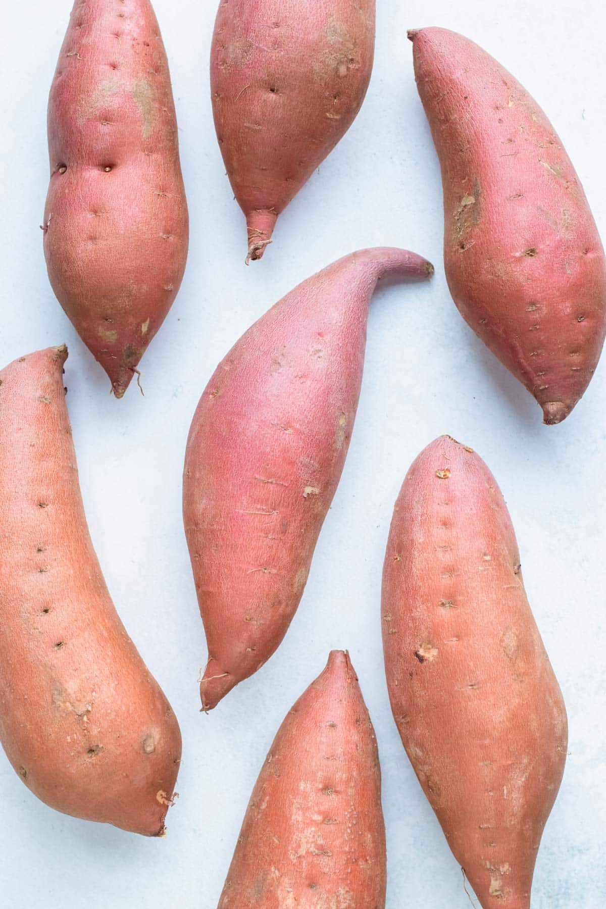 Russet and jewel sweet potatoes on a white board.