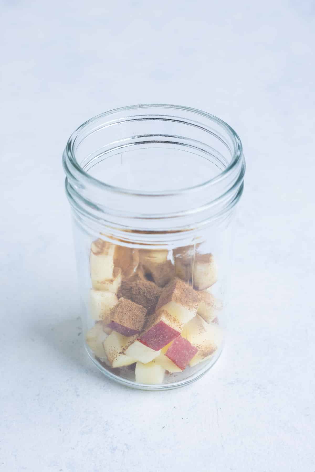 Apples and spices are in the bottom of the jar.