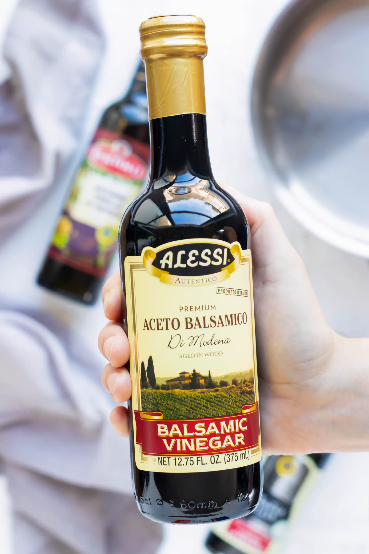 A bottle of balsamic vinegar being held for a balsamic reduction recipe.