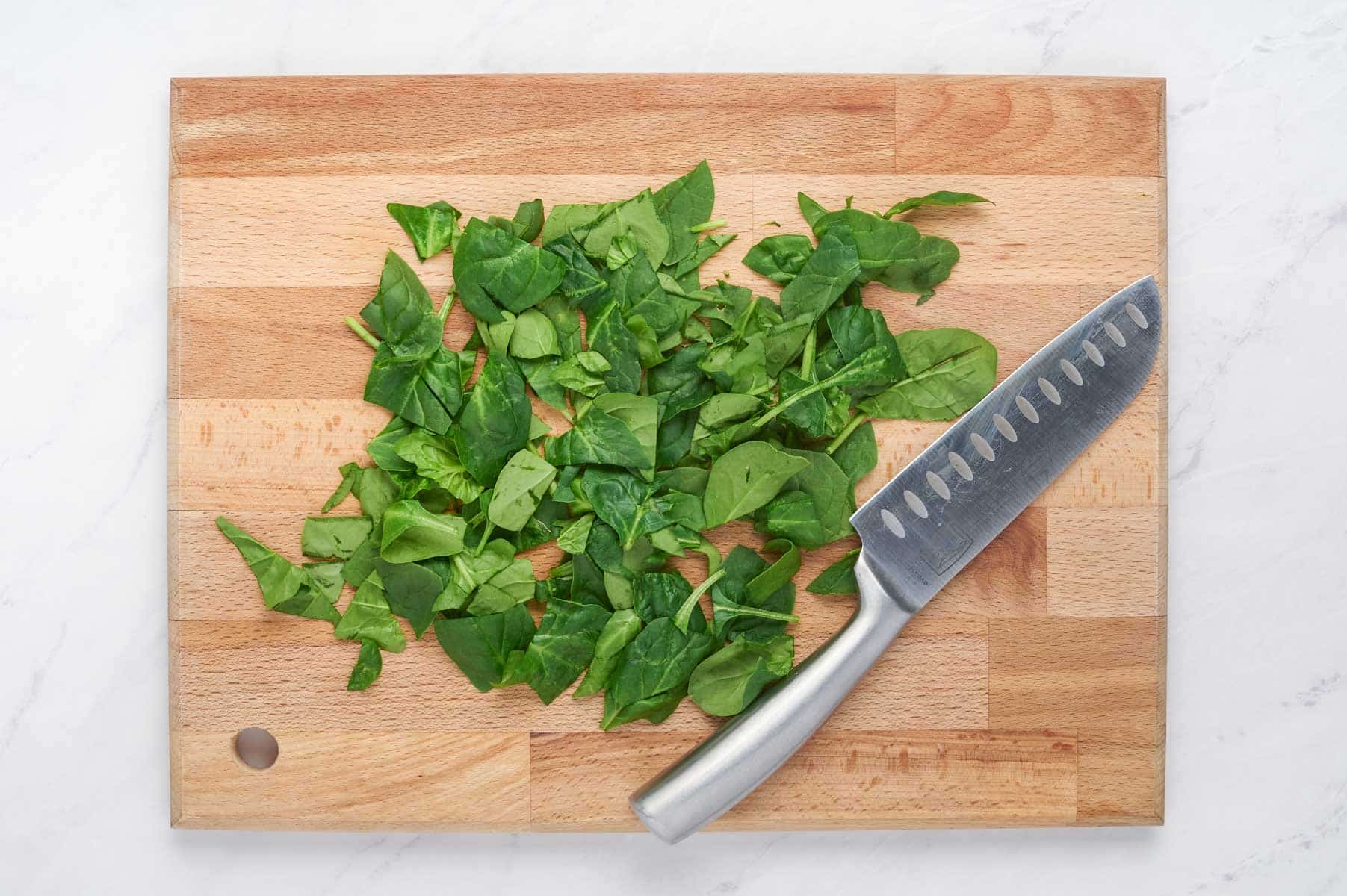 Spinach is chopped on a cutting board.