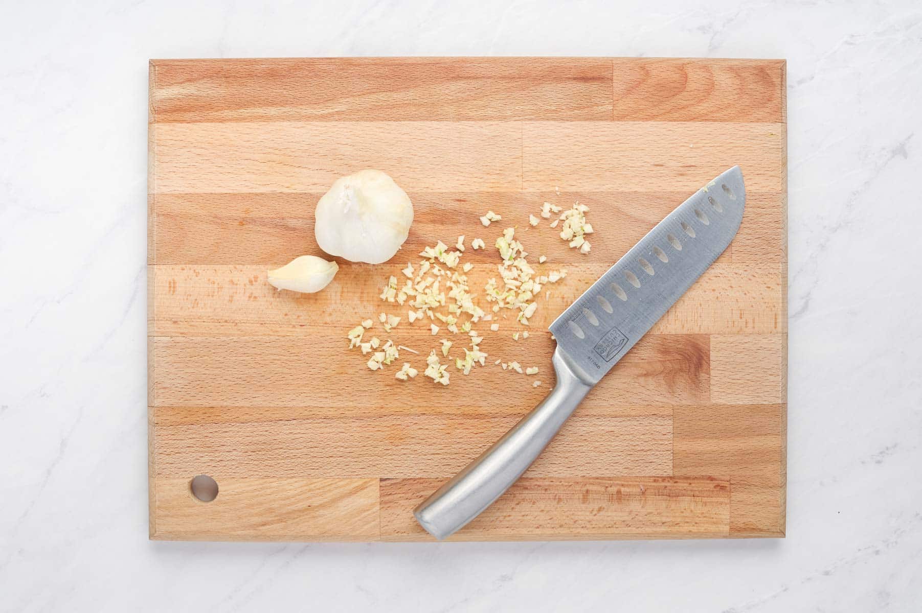 Garlic is chopped on a cutting board.