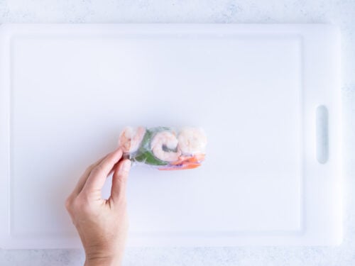 Showing how to carefully roll a spring roll.