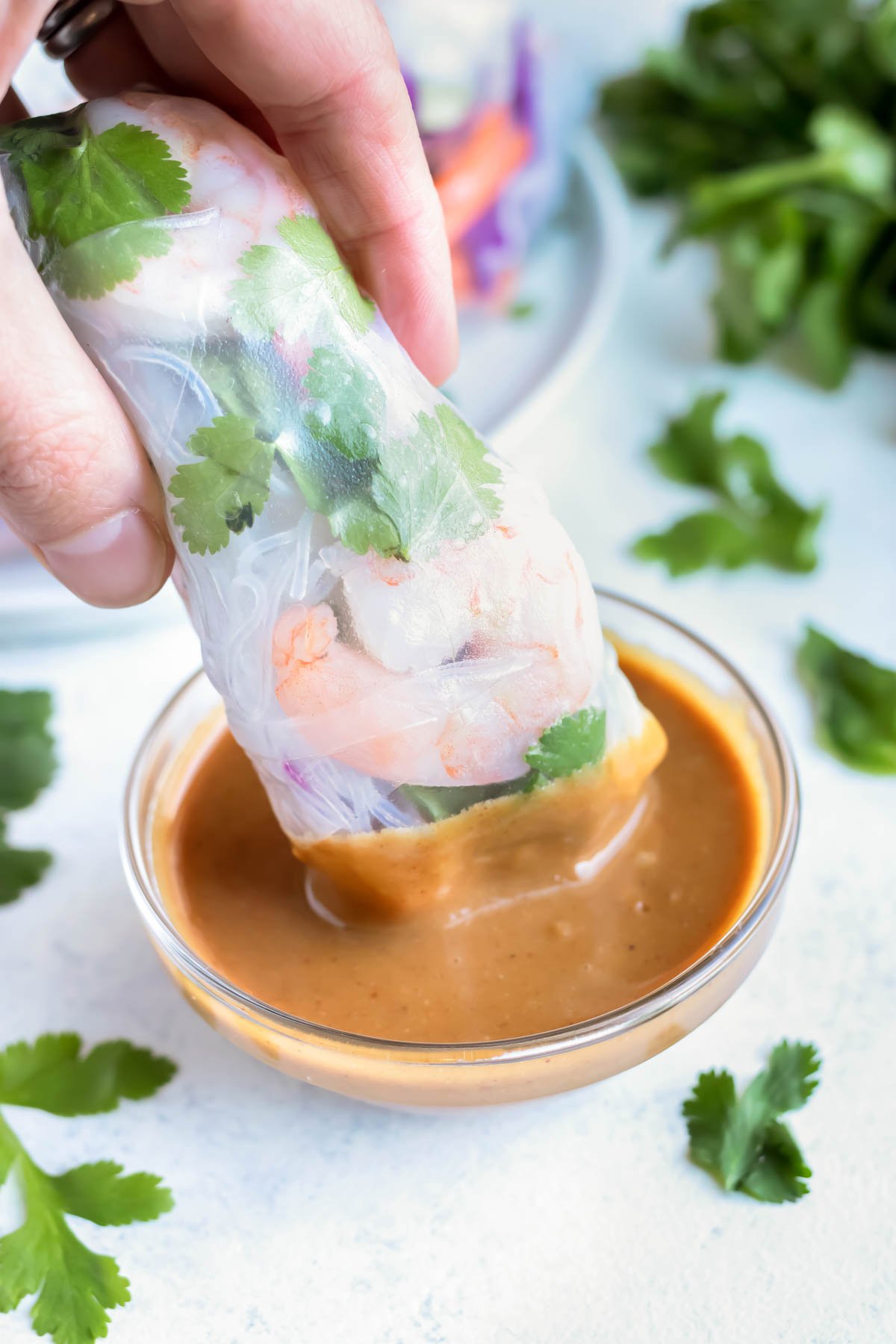 A spring roll is dipped into a homemade peanut sauce.