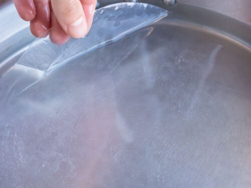 Rice paper is softened in a tray of water.