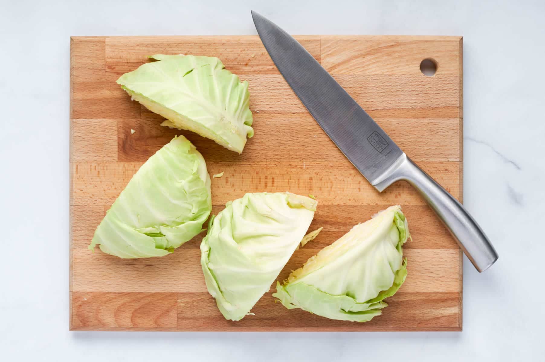 Cabbage is quartered on a cutting board.