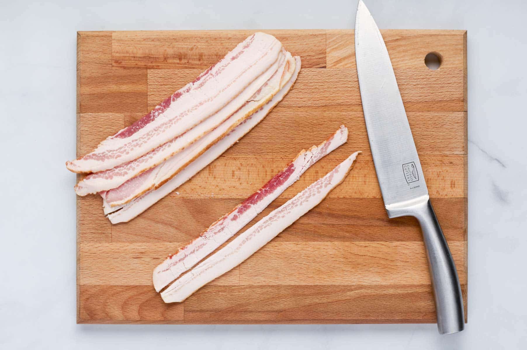 Bacon slices are on a cutting board with a knife.